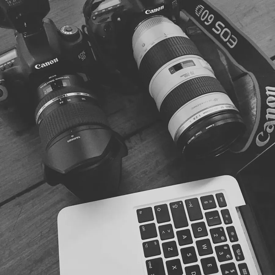 Câmaras fotográficas e um portátil em cima de uma mesa