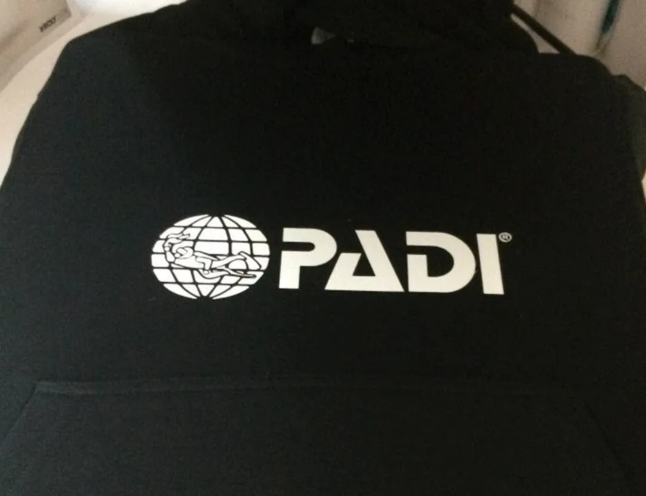 Logótipo PADI estampado em branco numa peça de roupa preta