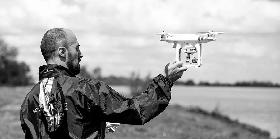 Operador a lançar um drone junto a um rio